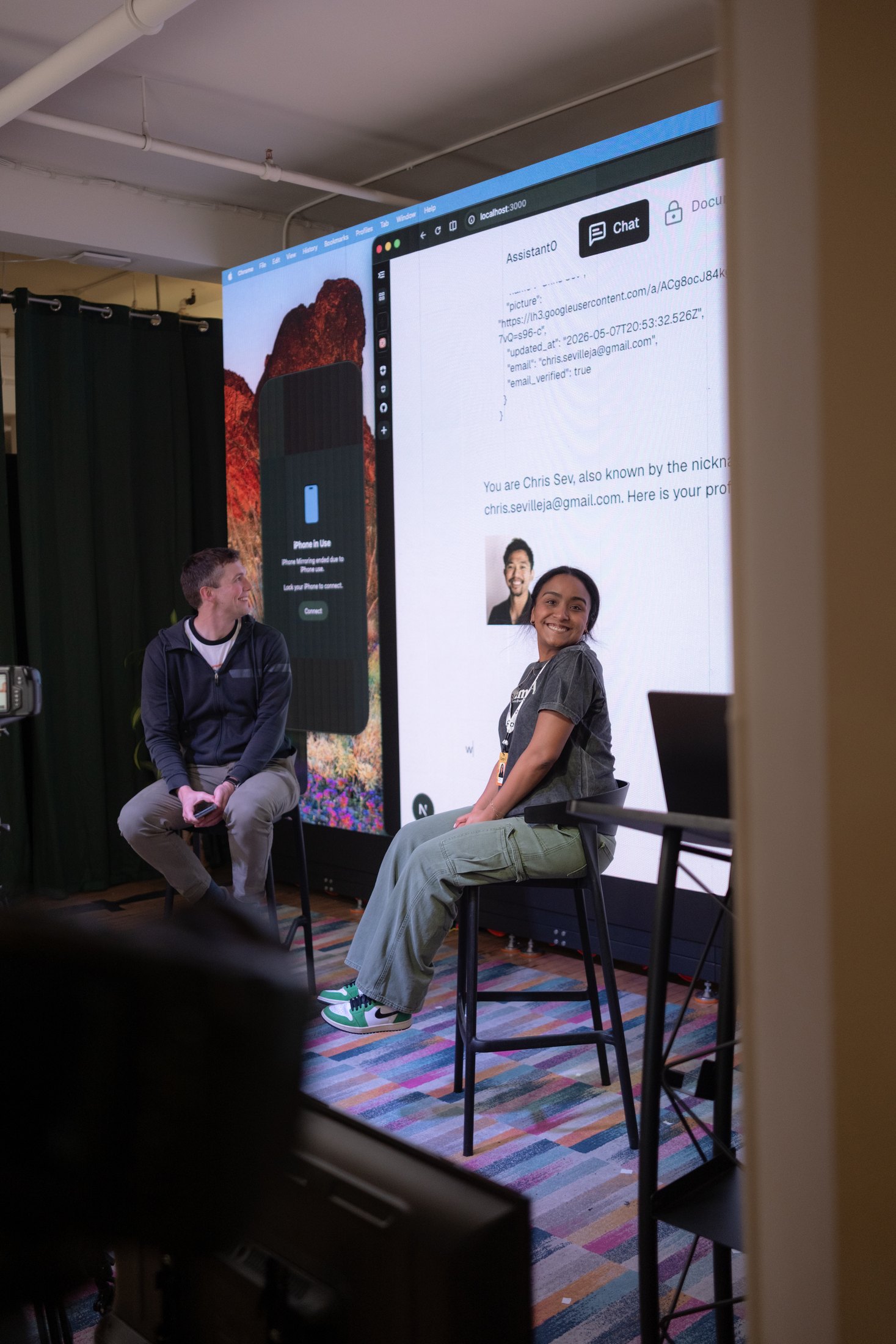 Calah Vargas on stage at a Camp AI event with a product demo projected behind her